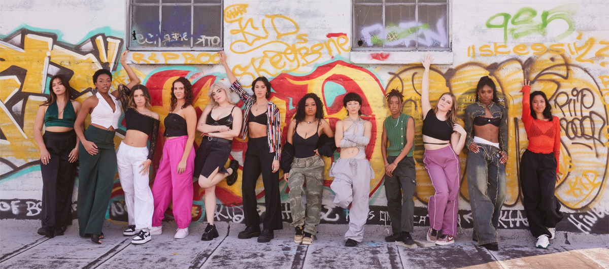 a group of women posed on a graffiti art wall.